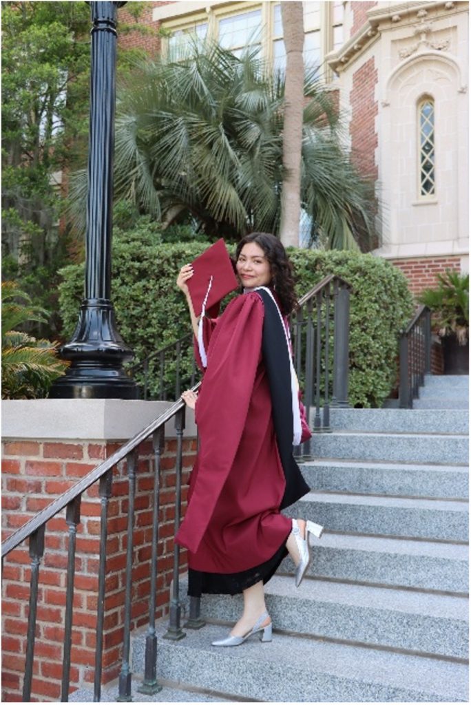 person posing in a red graduation gown